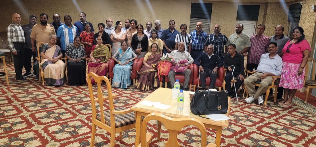 Community members gathered around seated guests with flowers